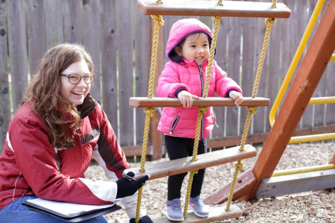 Listen and Talk Blended Classroom student playing outdoors on a playground set with a teacher of the deaf