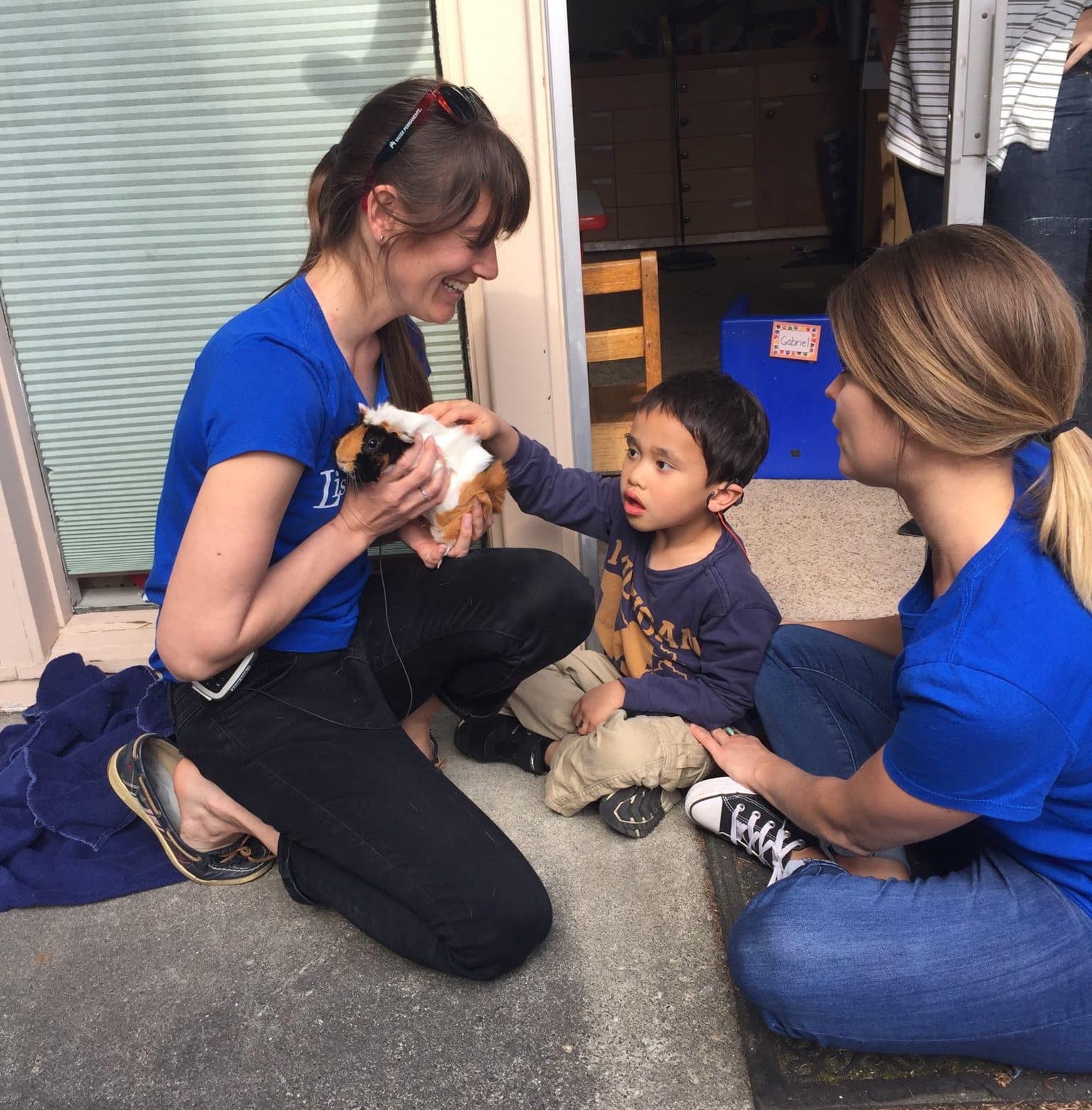 Two Listen and Talk team members with a student who is deaf and hard of hearing.