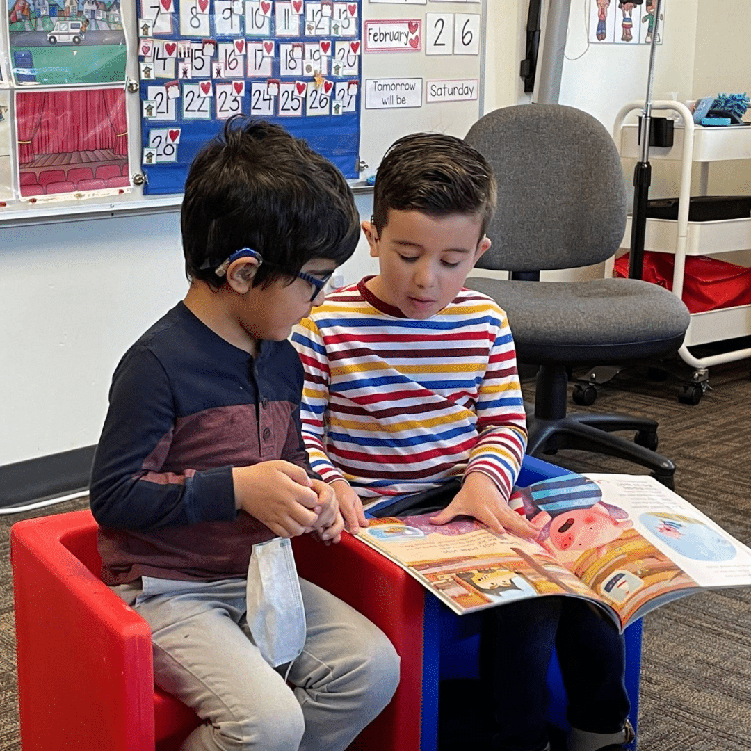 Two deaf kids enrolled in Listen and Talk's deaf preschool in Washington State reading a library book together.