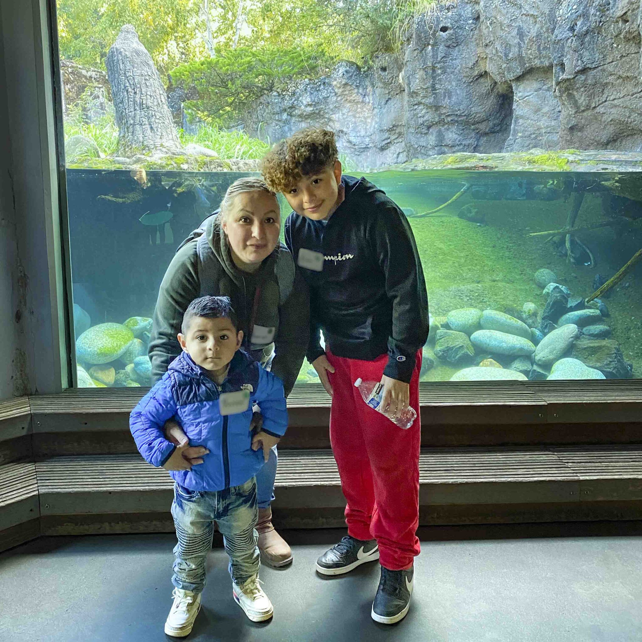 Group photo of family posing for camera standing in front of a glass aquarium tank
