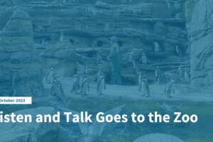 Blue Banner with an image of penguins in the background standing on rocks and in the water near a zookeeper who's feeding them. On the bottom left hand corner is a white rectangle with text stating "October 2023" followed by a white text title: Listen and Talk Goes to the Zoo.